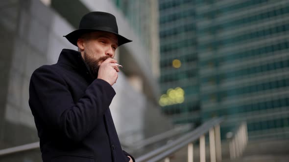 Spy or Undercover Policeman is Smoking Cigarette Outdoors in City and Stalking Someone