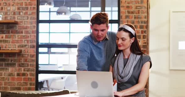 Businesswoman interacting with coworker while working on laptop