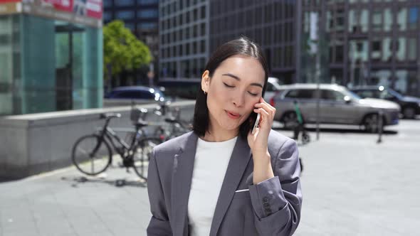 Young Asian Business Woman Making Call on Cellphone Standing in Big City