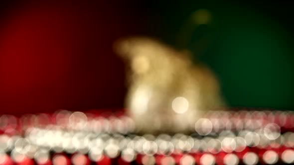 Shiny Unusual Gold Toy for Christmas or New Year and Beads, Rotation, on Red and Green, Bokeh