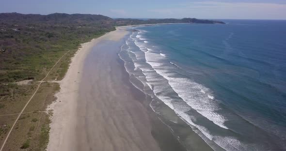 Aerial drone view of the beach, rocks and tide pools in Guiones, Nosara, Costa Rica.