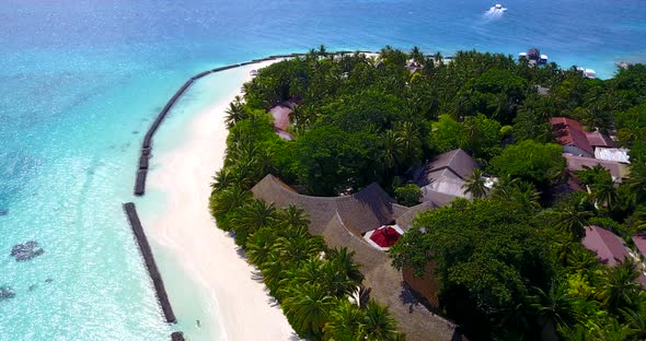 Wide angle flying tourism shot of a sunshine white sandy paradise beach and aqua blue ocean backgrou