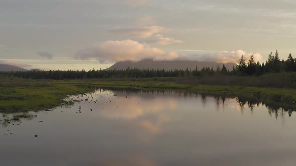 Aerial flight flat calm reflective water showing wilderness sunrise mountain scenery