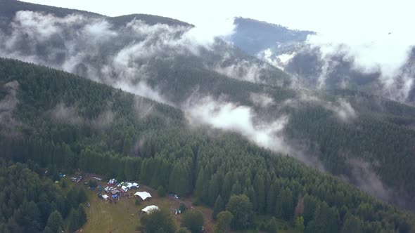 Aerial Drone Shot of a Festival Campground Punching in to Reveal the Vastness of the Romania Mountai