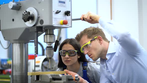 Instructor explaining drilling machine in factory