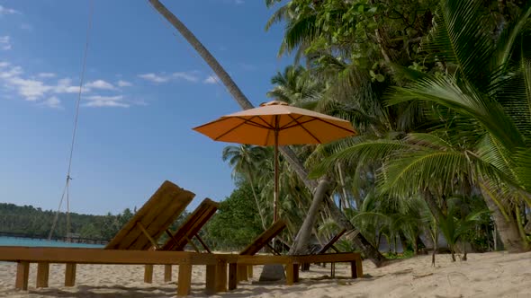 Beach beds  with umbrella on white sandy beach. Koh Kood, Thailand. PAN RIGHT TO LEFT