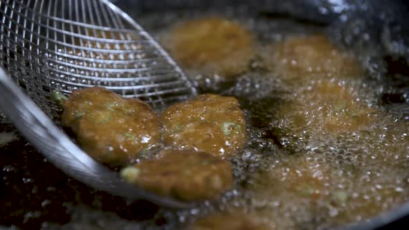 Deep Frying Tod Man Pla Thai Fish Cakes in Hot Oil with Skimmer - Close Up