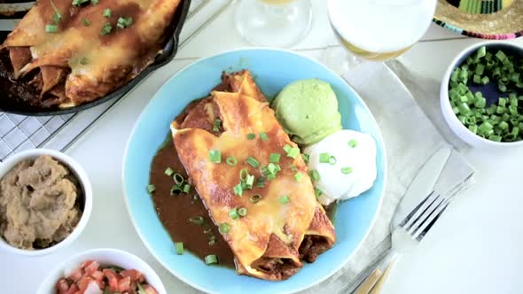Dinner plate with Chicken enchiladas garnished with green onions and sour cream.