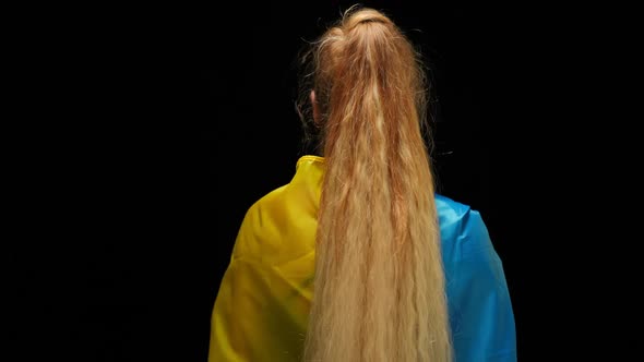 Back View Woman in Ukrainian Flag Standing at Black Background Turning Looking at Camera with