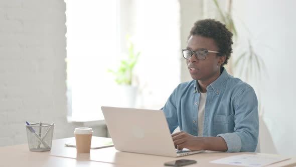 Young African Man Talking on Video Call on Laptop in Office