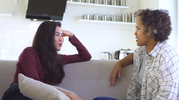 Two Girlfriends Gossiping While Sitting on the Couch