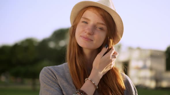 Closeup Beautiful Girl in Hat with Amazing Red Long Hair Smiling Looking at Camera During Bright