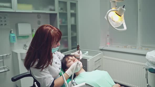 Professional stomatologist in mask working with patient at dental office