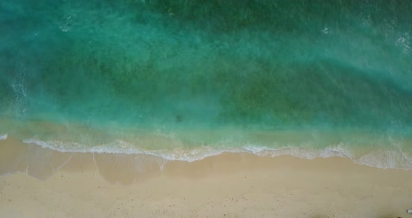 Daytime fly over copy space shot of a white sand paradise beach and blue sea background in 4K