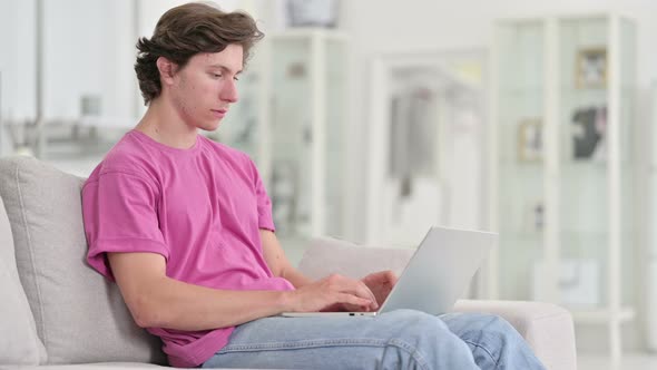 Attractive Casual Young Man Sitting at Home with Laptop 