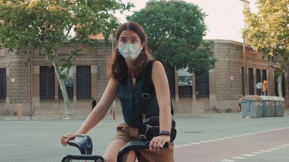 Young Woman Sport Activity In Medical Mask Rides Rent Ciry Bicycle in City Center After Quarantine