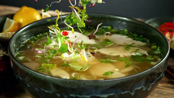 Super Slow Motion Detail Shot of Ingredients Falling Into Chicken Pho Soup at 1000 Fps