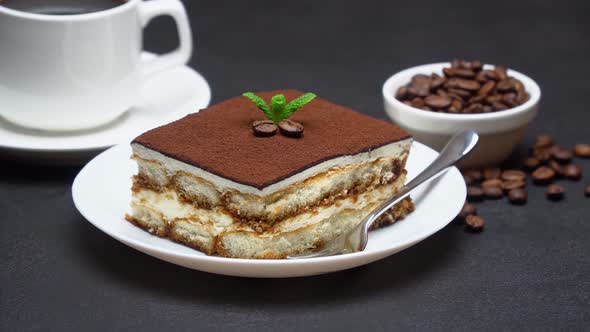 Portion of Traditional Italian Tiramisu dessert, cup of espresso coffee and coffee beans