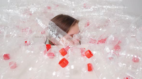 Dehydrated Sick Woman Is Lying in a Pile of Plastic Bottles. Environmental Pollution Problem. Stop