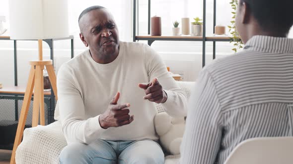 Middleaged Adult Elderly African Man Father Patient Sitting on Sofa Indoors Asks Question Talking to