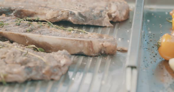 Close up slow motion shot of meat on a grilling plate in an outdoor luxury litchen