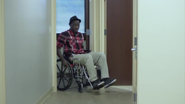 Man in wheelchair going down hallway.