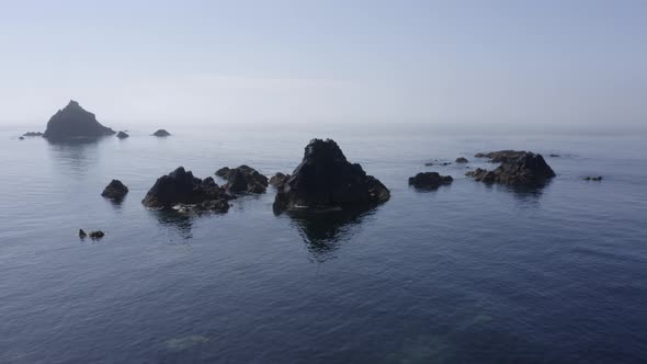 Calm water and misty coastal rock islets of South Ireland's Celtic Sea