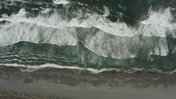 Ocean beach drone footage overhead of waves crashing into shore