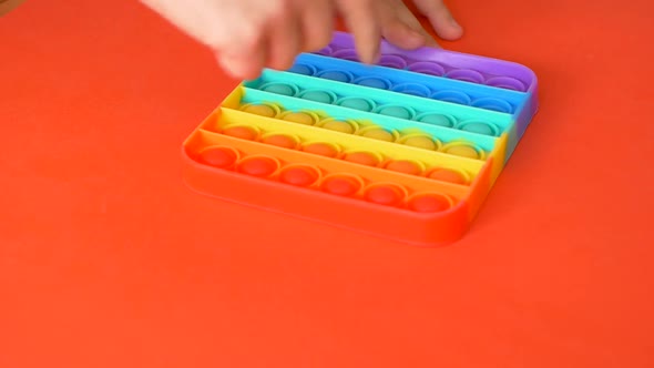 Close-up of a children's hand pressing on a colorful pop it.