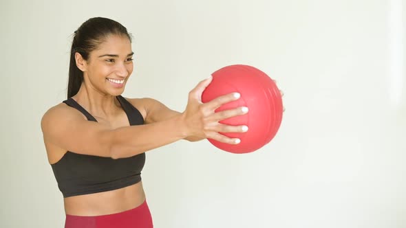 Smiling ethnic sportswoman exercising with fit ball