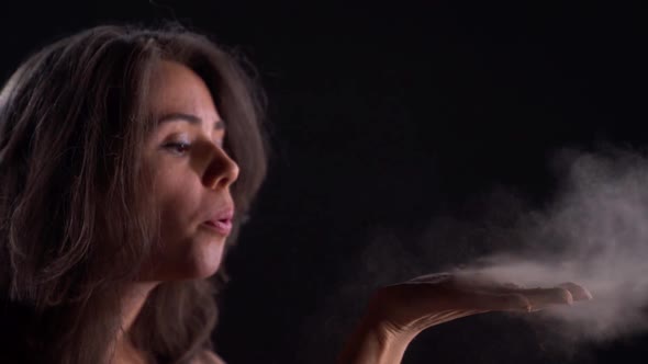 Young Woman Is Blowing Out a Dust or Powder From Her Hand in Darkness, Dancing By Palms, Closeup