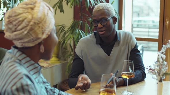 Cheerful African American Man Chatting With Girlfriend in Cafe