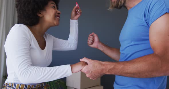 Happy mixed race couple holding house keys at new apartment house