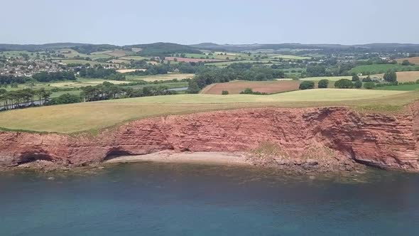 Aerial DOLLY ZOOM of red cliffs along the Jurassic Coast and Devon countryside