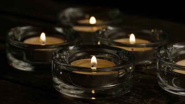 Tea candles with flaming wicks on a wooden background - CANDLES 021