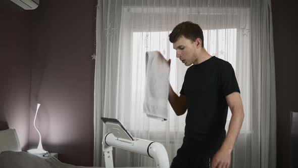 Athlete wipes sweat with towel after intense cardio exercise on treadmill