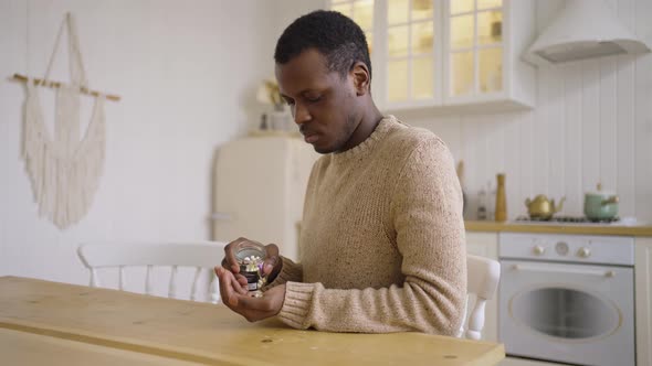 Sad Black Man Pours a Handful of Antidepressant Pills Into His Hand and Looks Thoughtfully Out the