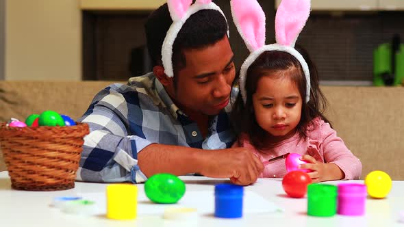 Happy Mixed Race Family Celebrating Easter Painting Eggs with Brush Smiling and Laughing