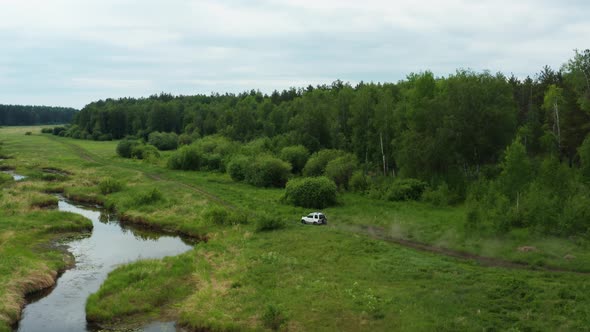 Aerial View of a Car Driving in Nature Near the River