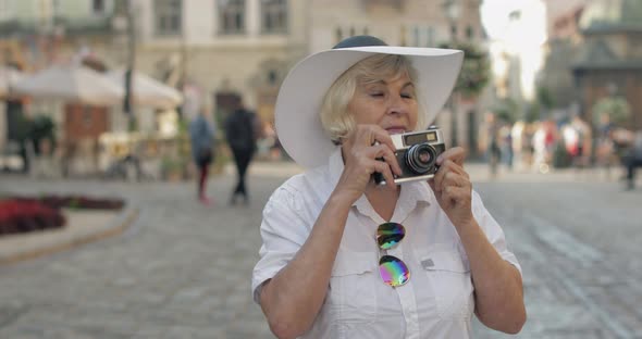 Senior Female Tourist Exploring Town and Makes a Photo with Retro Photo Camera