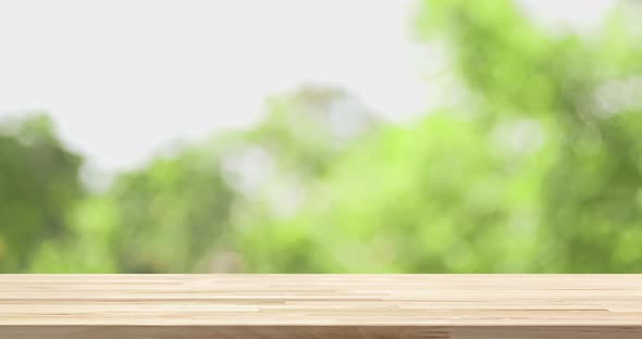 Wood table top with blur natural green foliage bokeh in background for product display mockup