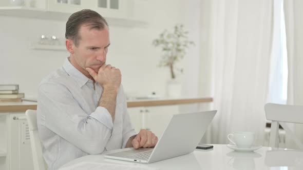 Middle Aged Man Thinking and Working on Laptop at Home 