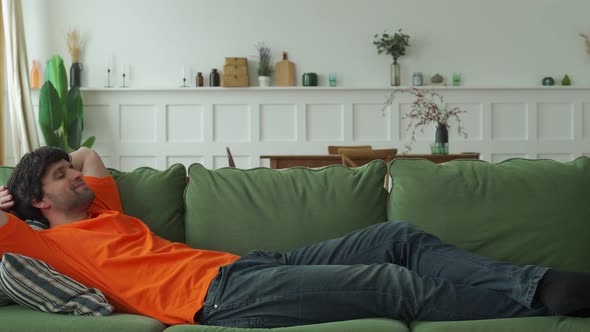 Happy Man Is Resting on a Comfortable Sofa Resting with His Eyes Closed