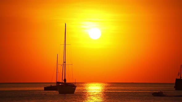 Sail boat in tropical sea at beautiful sunset or sunrise sky with Reflected sun on water surface