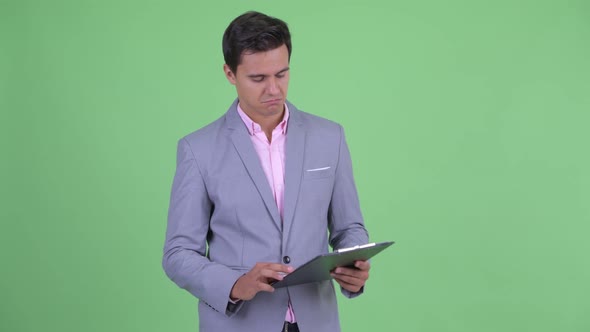 Happy Young Handsome Businessman Talking While Holding Clipboard