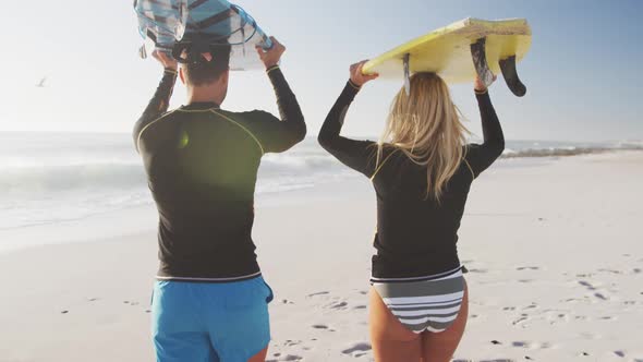 Caucasian couple holding surfboards on the beach