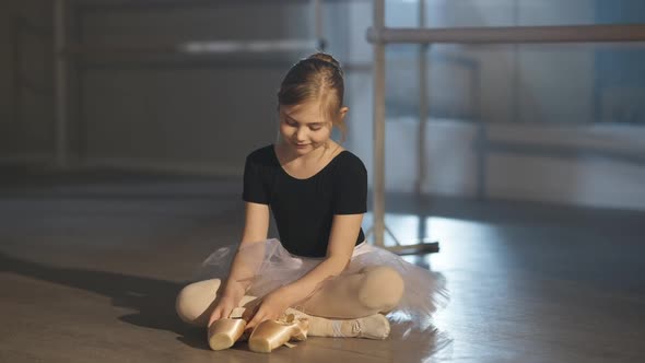 Motivated Talented Hardworking Girl in Tutu Admiring Beige Pointes Sitting on Floor in Ballet Studio