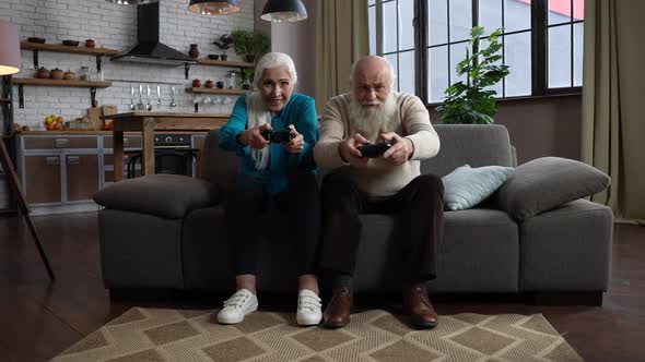 Excited Aged Couple Playing Computer Game at Home