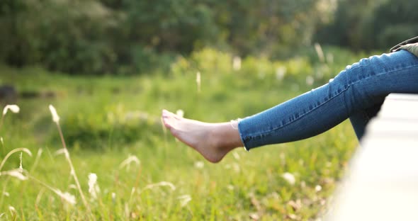 Woman sitting on the wooden walking path and swing the legs