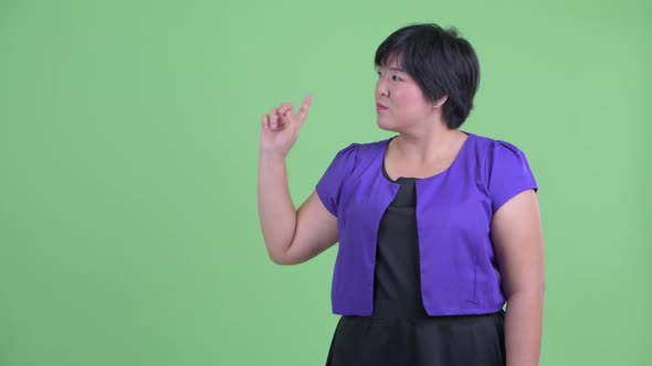 Happy Young Overweight Asian Woman Touching Something and Looking Surprised